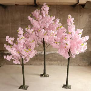 3 alberi di ciliegio artificiali di dimensioni diverse in una stanza con pavimento beige.