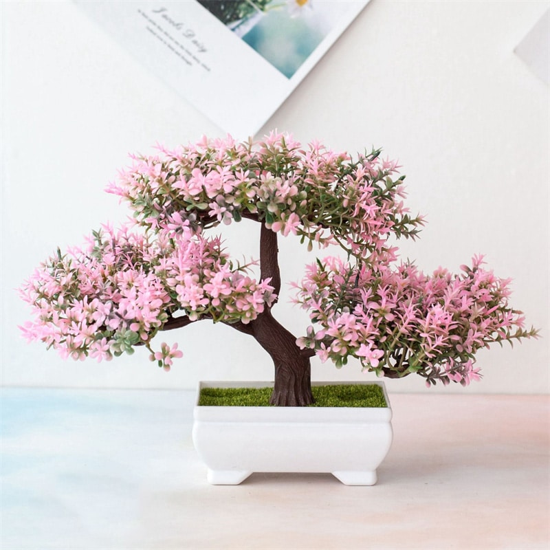 Un bonsai rosa in un vaso bianco.