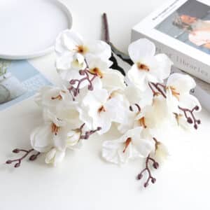 Piccolo bouquet di magnolie bianche di plastica su un tavolino basso con un piatto e un libro