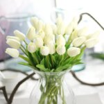 Un bouquet di tulipani bianchi in un vaso trasparente su un tavolo.