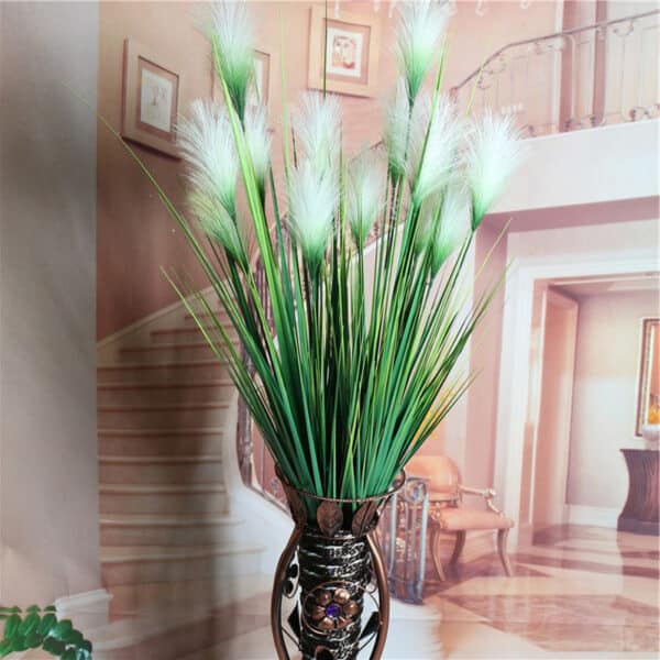 Canne artificiali verdi e bianche in un vaso davanti a una scala.