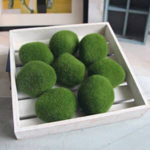 8 palline di muschio verde artificiale in una piccola cassa di legno bianca.