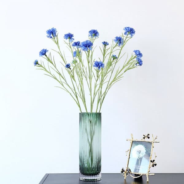 Bouquet di fiori artificiali blu in un vaso su un mobile.