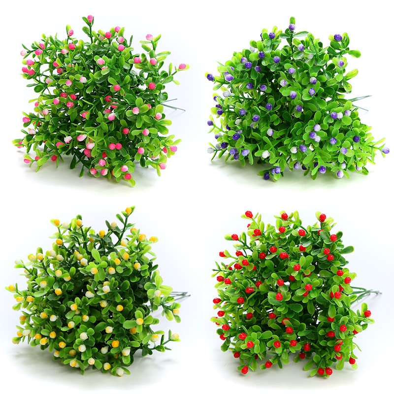 Quattro piante artificiali con palline colorate su sfondo bianco.