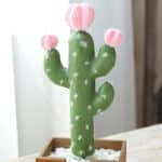 Foto di un cactus artificiale con 3 piccoli fiori rosa in un vaso
