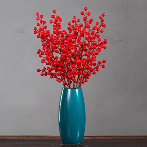 Bacche rosse in un vaso blu su un tavolo di legno