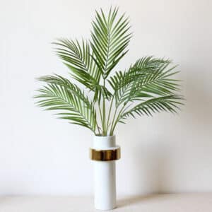 Foto di rami di palma artificiali in un vaso bianco.